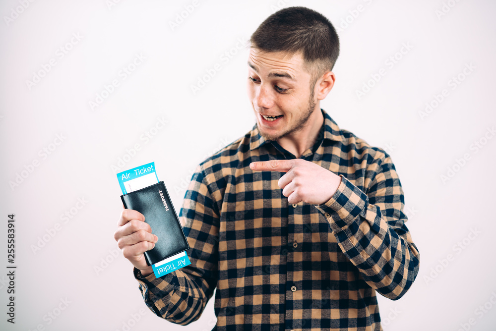 a handsome man in a plaid shirt against a brick wall with your passport and tickets inside a handsome man in a plaid shirt against a brick wall with your passport and tickets inside