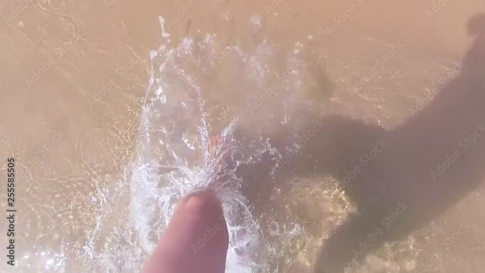 Closeup top view of beautiful female legs with pink manicured toes walking underwater. Point of view of woman walking in sea water at sandy beach of hotel resort Video footage shoot with action camera