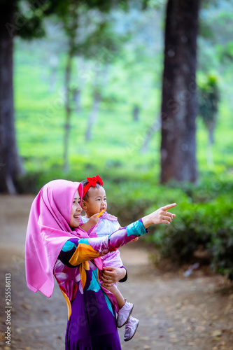 A happy Muslim mother with her daughter have fun at tea farm in Java Indonesia