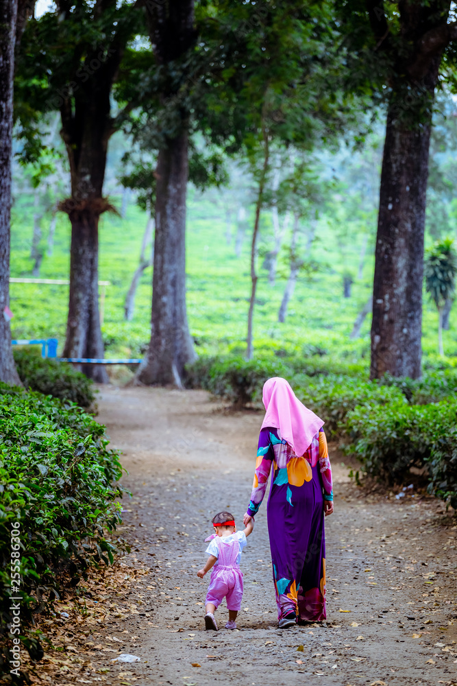 A happy Muslim mother with her daughter have fun at tea farm in Java Indonesia A happy Muslim mother with her daughter have fun at tea farm in Java Indonesia