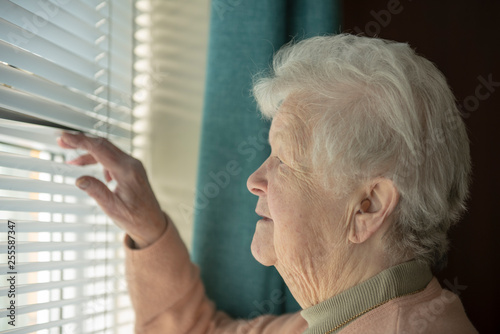 Obraz na plátně Senior woman spying through window blinds