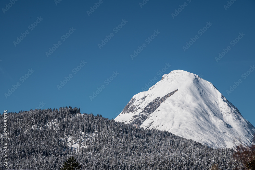 Schneebedeckter Berggipfel mit Wald und blauem Himmel, Alpen, Bayern, Mittenwald, Deutschland