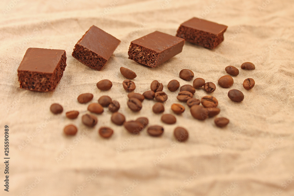 Milk porous chocolate sweets with coffee beans on a linen texture background. Milk porous chocolate sweets with coffee beans on a linen texture background.
