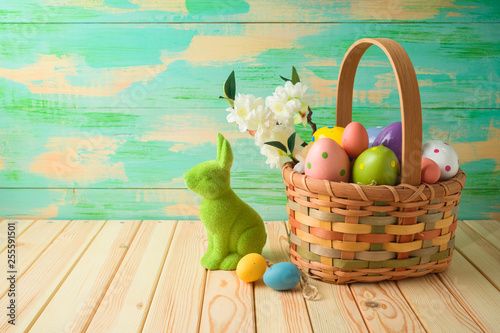 Sticker Easter holiday background with easter eggs in basket and bunny on wooden table