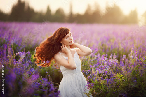 Outdoor portrait of a beautiful middle aged woman in a flowered field. The blossoming a galega a medicinal Galega officinalis. Purple flower. Happy young lady and spring summer nature, harmony concept photo