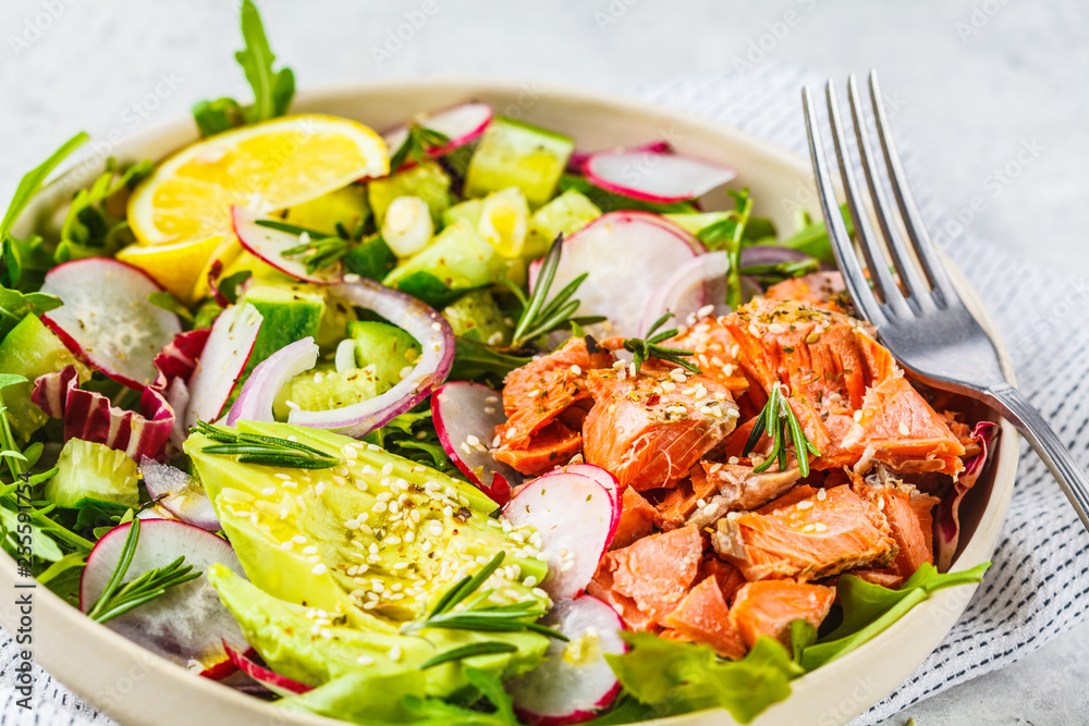 Baked red fish salad with avocado, cucumber, radish and arugula in white plate. Baked red fish salad with avocado, cucumber, radish and arugula in white plate.