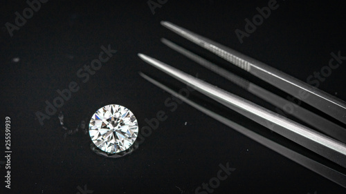 2.50 carat size diamond compared with tweezers on black reflection background © pv