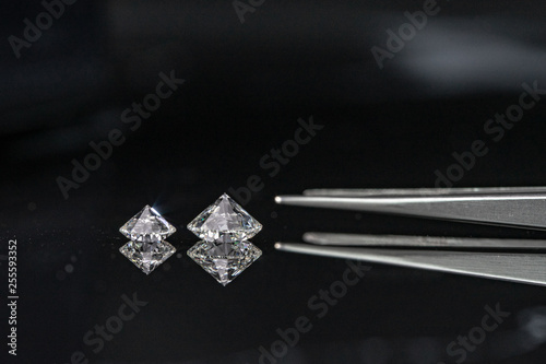 Fototapeta Naklejka Na Ścianę i Meble -  1.00 carat size and 2.50 carat size bottom up diamonds with tweezers on black background