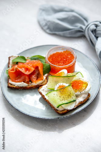 Smorrebrod - danish open sandwich with red caviar, fish, vegetables, cheese on marble background. Top view with copy space