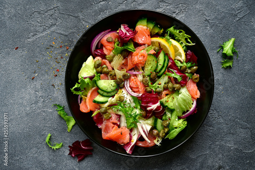 фотографія Vegetable salad with salted salmon in a black bowl