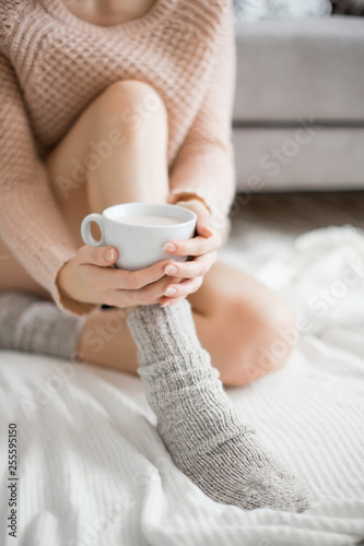 Woman in a cozy room with a cup of cocoa in her hand.