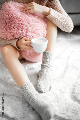 Woman in a cozy room with a cup of cocoa in her hand.