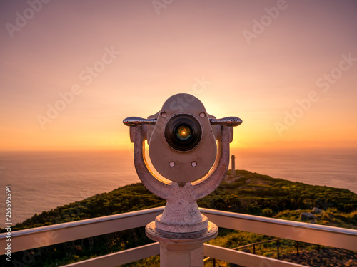 Image of viewpoint with binoculars during colorful sunset pointing at the ocean photo