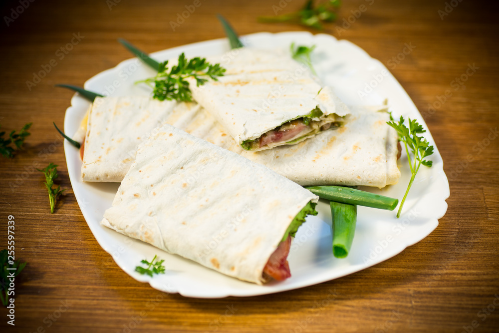 roll of pita with lettuce leaves, greens and sausage in a plate roll of pita with lettuce leaves, greens and sausage in a plate
