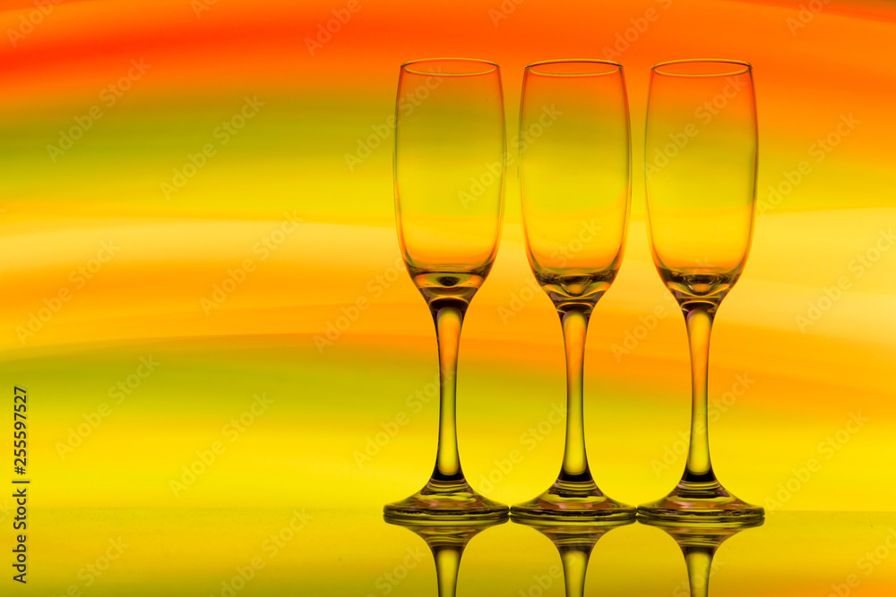 Three champagne glasses / flutes in a row with colorful multicolored light painting behind them