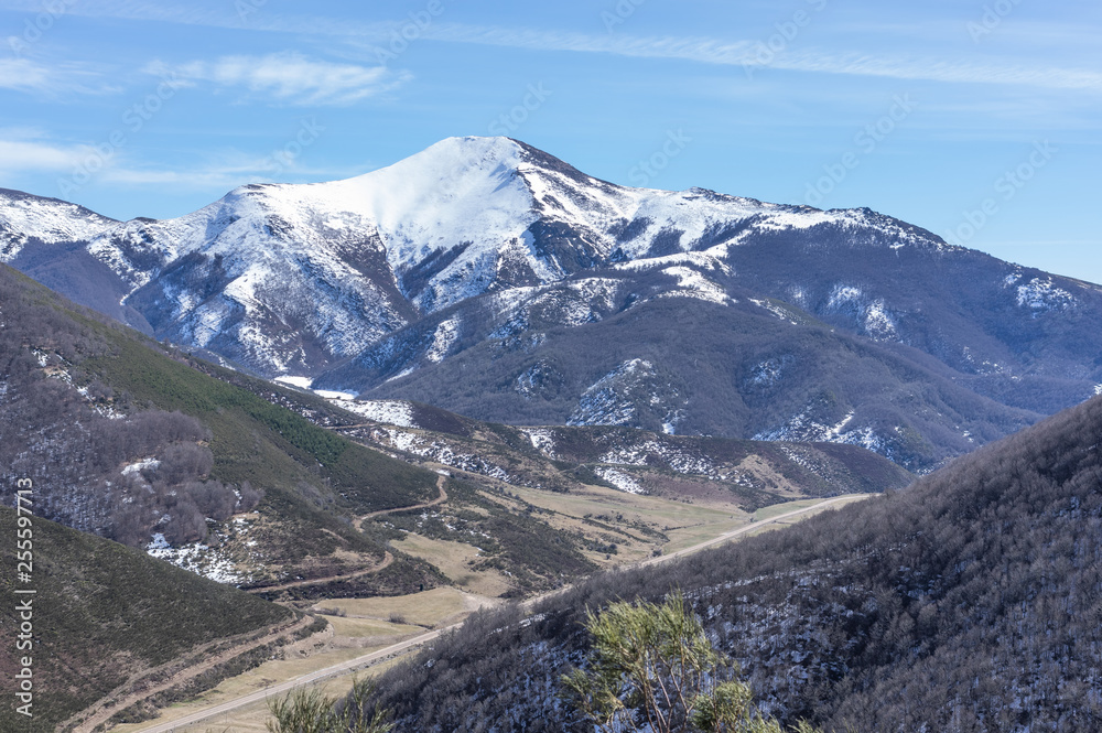 Photograph of the top of the valley full of snow with the snowy mountains in the background in the area of Picos de Europa de Leon, Spain.