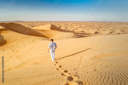 Dubai, young men walking at the sand dunes of Duba desert photo