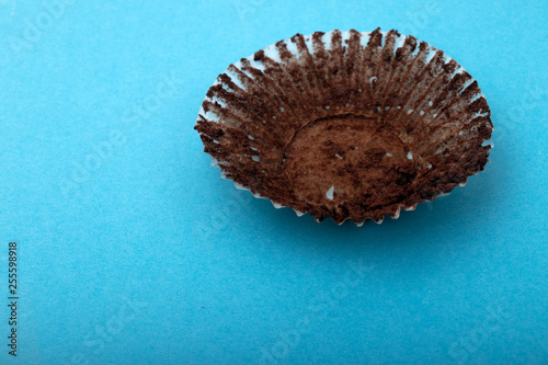 Empty chocolate muffin wrapper on a blue background