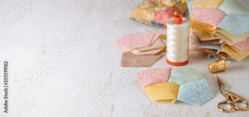 Stitched quilting block from four pentagons, piles of blocks and pentagons, sewing accessories. Space for text