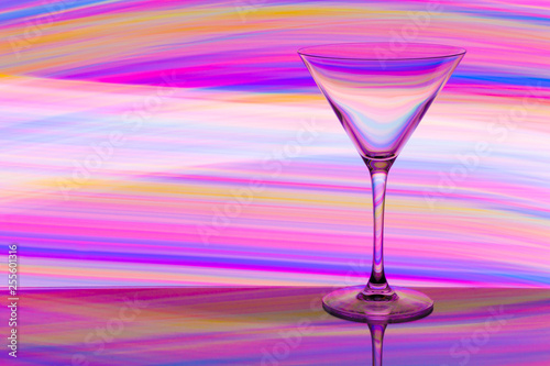 A cocktail / martini glass with colorful streaks of light painting behind