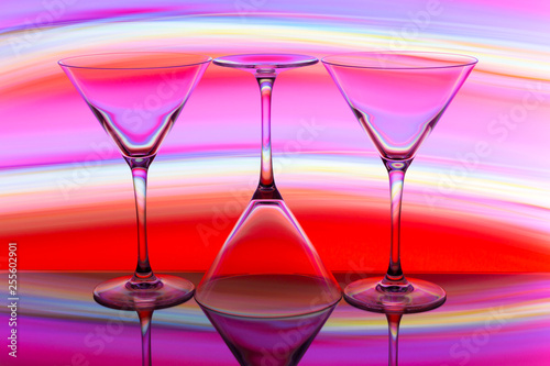 Three cocktail / martini glasses in a row with colorful streaks of light painting behind