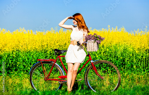 Redhead girl with bike and flowers in basket