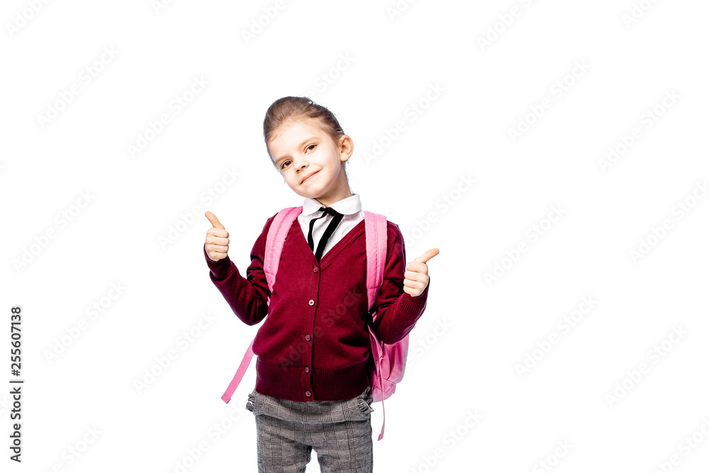 Back to school. Beautiful little girl dressed like a School girl - in white shirt, red blouse and gray pants hold a school bag and posing like model - show thumb up. Isolated on white. Back to school. Beautiful little girl dressed like a School girl - in white shirt, red blouse and gray pants hold a school bag and posing like model - show thumb up. Isolated on white.
