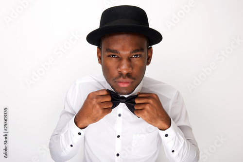 male fashion model adjusting his bowtie by white background