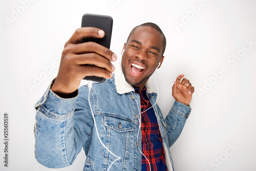 happy young black guy listening to music with smart phone and earphones and dancing