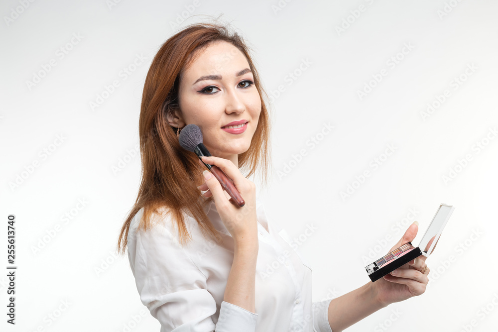 Makeup artist, beauty and people concept - Beautiful korean young woman holding palette of colorful eye shadows and brushes on white background Makeup artist, beauty and people concept - Beautiful korean young woman holding palette of colorful eye shadows and brushes on white background