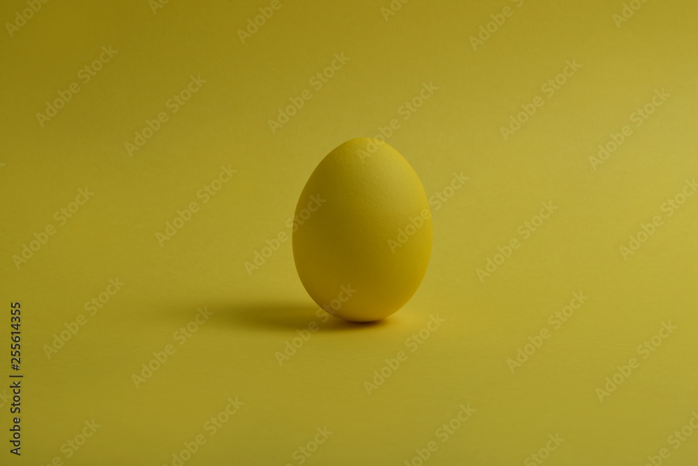 One yellow painted Easter egg stand on a yellow background. One yellow painted Easter egg stand on a yellow background.