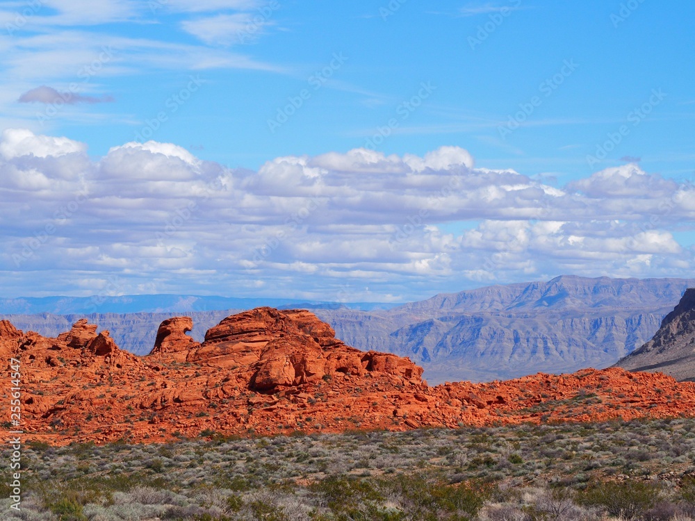 view of red rocks and mountains with clouds and sky in valley of fire