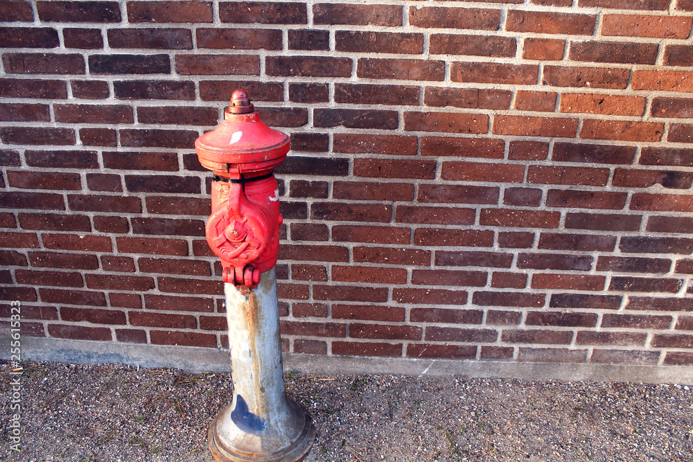 Red fire hydrant on a European street near a red brick wall Red fire hydrant on a European street near a red brick wall