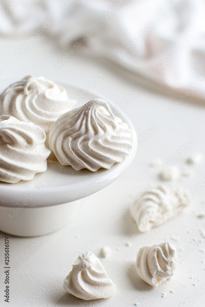 white meringues on a small plate white background negative space