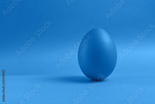 Blue egg on blue background. A blue colored painted egg isolated on blue background. Happy Easter card , copy space. Blue monochrome Easter