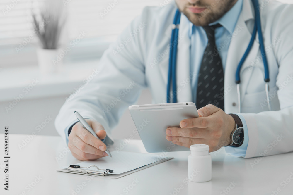 Doctor uses the tablet while sitting in his office Doctor uses the tablet while sitting in his office