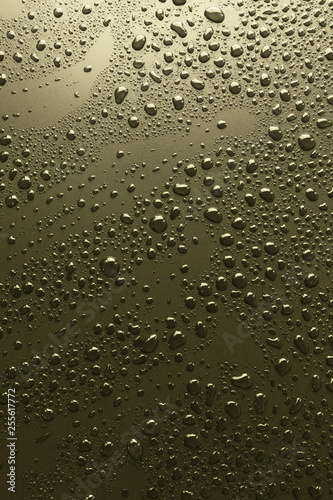 Shiny water drops on golden metal surface, background
