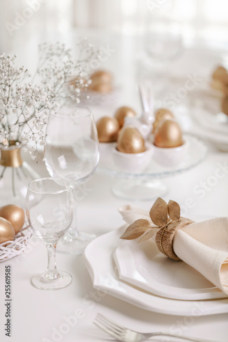 Happy Easter  Golden decor and table setting of the Easter table with white dishes of white color.