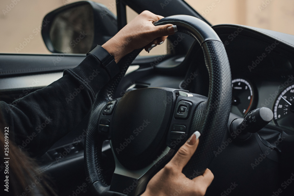 Women's hands on the wheel of a car while driving