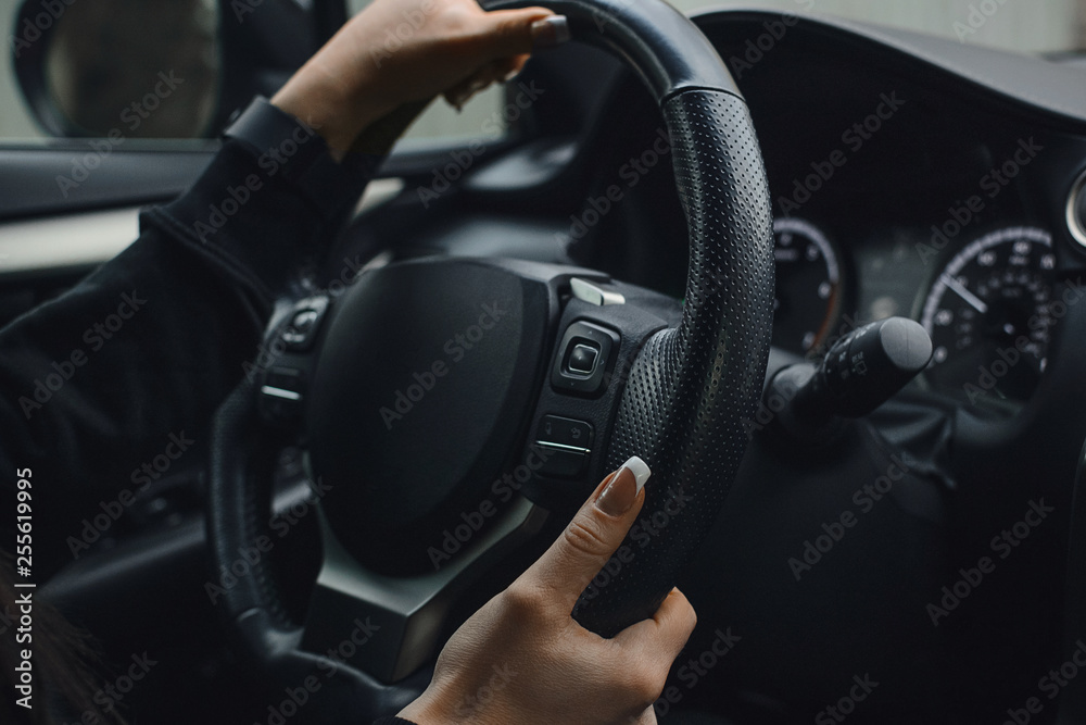 Women's hands on the wheel of a car while driving