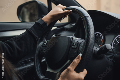 Women's hands on the wheel of a car while driving