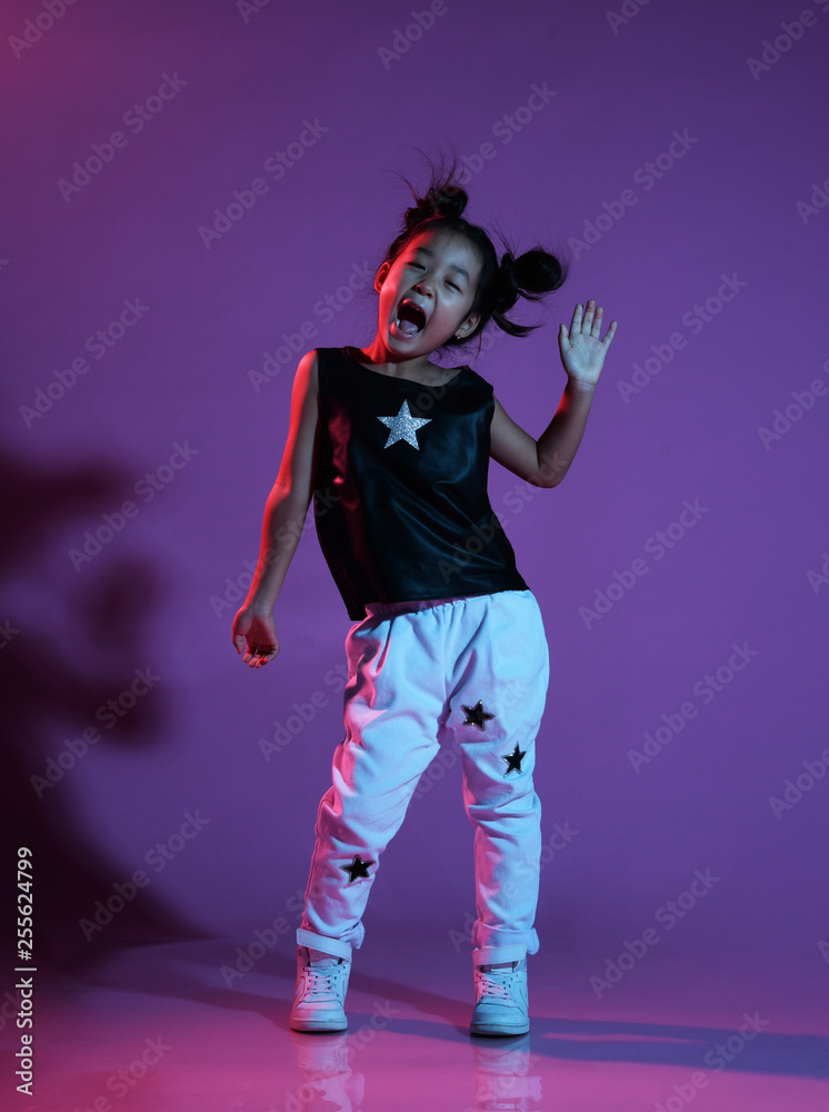 Asian kid girl in shirt and pants with stars and white sneakers greets and shouts joyfully