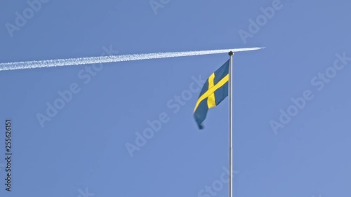 Swedish flag waving on the wind while plane flies in the background. photo