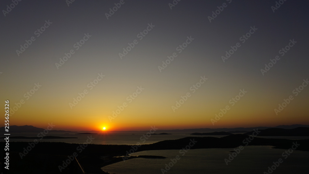 Blazing sunset over Aegean Sea (Ege Denizi) in Seytan Sofrasi (Devil's Table), Ayvalik, Turkey. Bright dramatic sky, dark ground. Scenic colorful sky at sunset landscape. Sun over skyline, horizon.