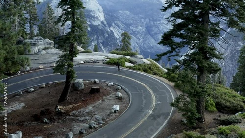 Teen skating down a beautiful windy roads with pine trees and mountains during fall photo