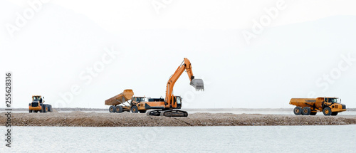 bulldozers, trucks do construction work on the background of the sea photo