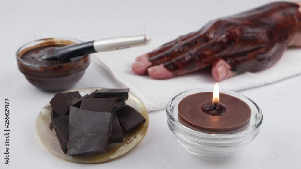 Female hand covered with chocolate hand mask on a white background. Accessories for spa treatments and aromatherapy with chocolate as the main ingredient. Female hand covered with chocolate hand mask on a white background. Accessories for spa treatments and aromatherapy with chocolate as the main ingredient.