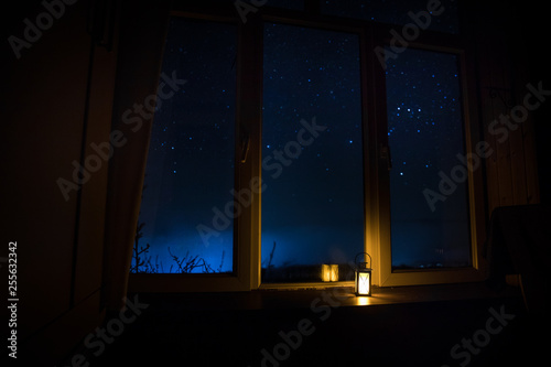 Night scene of stars seen through the window from dark room. Night sky inside dark room. Long exposure shot