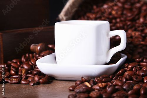 Fresh roasted coffee beans in burlap sack  coffee cup and grinder on dark background.