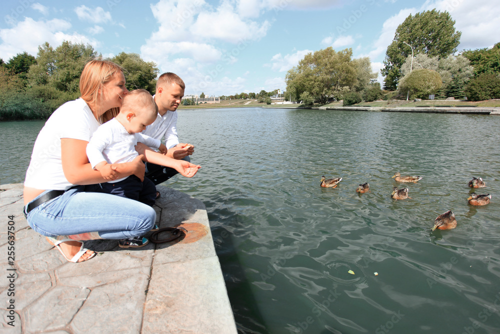 happy parents with their little son sitting on the lake pier happy parents with their little son sitting on the lake pier
